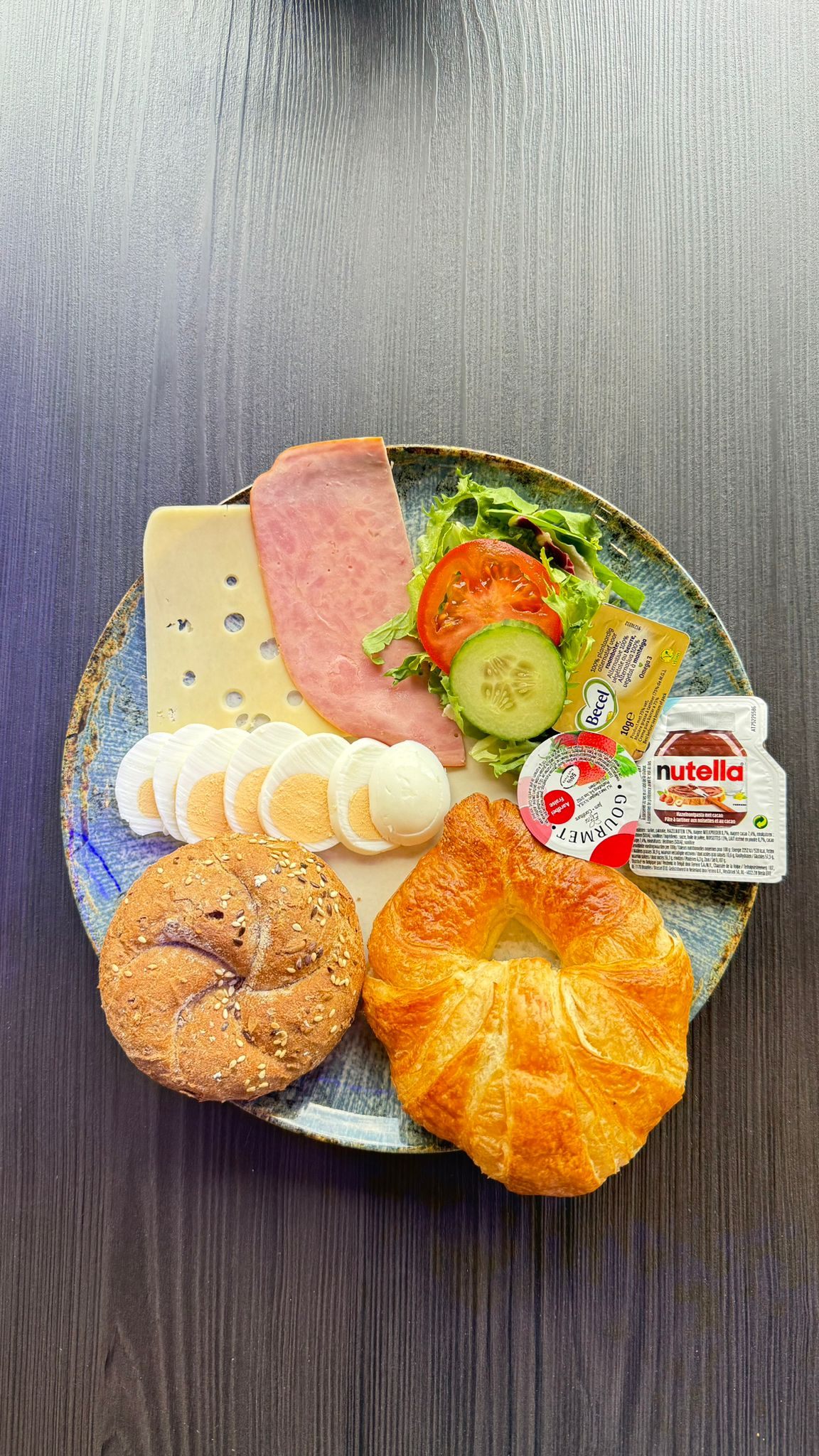 Ontbijtbord met croissant, sandwich, kaas, ham en eitjes